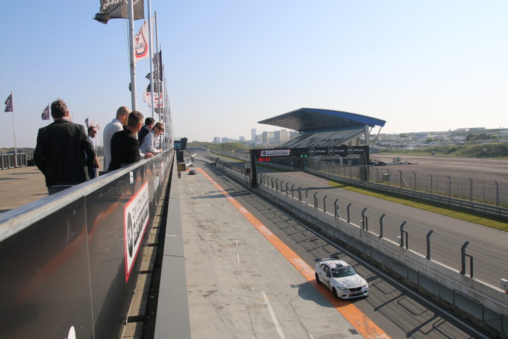 some guests watch the hot laps of circuit Zandvoort while getting a tour