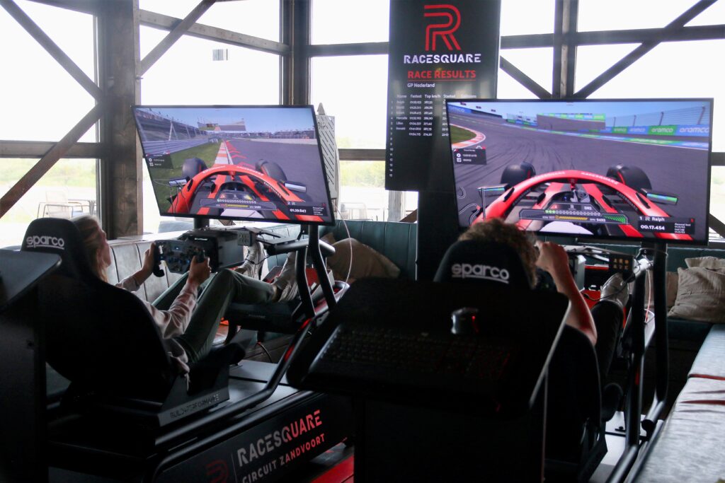 een aantal gasten racen tegen elkaar in een f1 simulator
